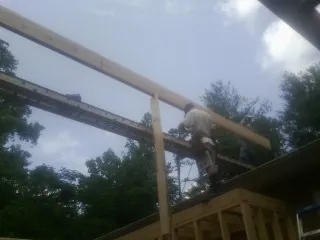 Carpenter setting a ridge beam over a new addition frame — Ice Dam Removal by Roofing Brothers in Portage